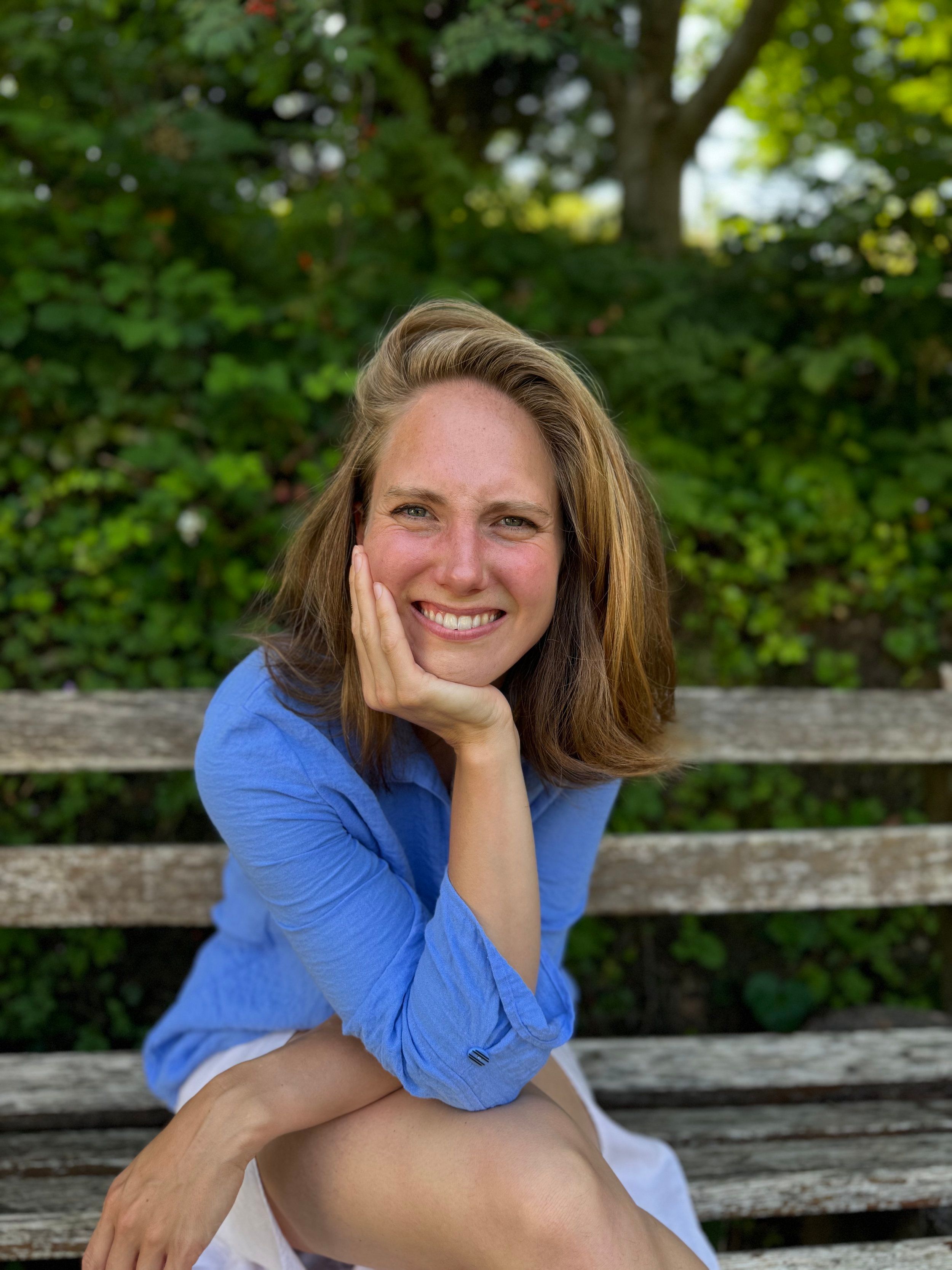 Katherine Kaufmann smiling on a garden bench, chin resting on her hand